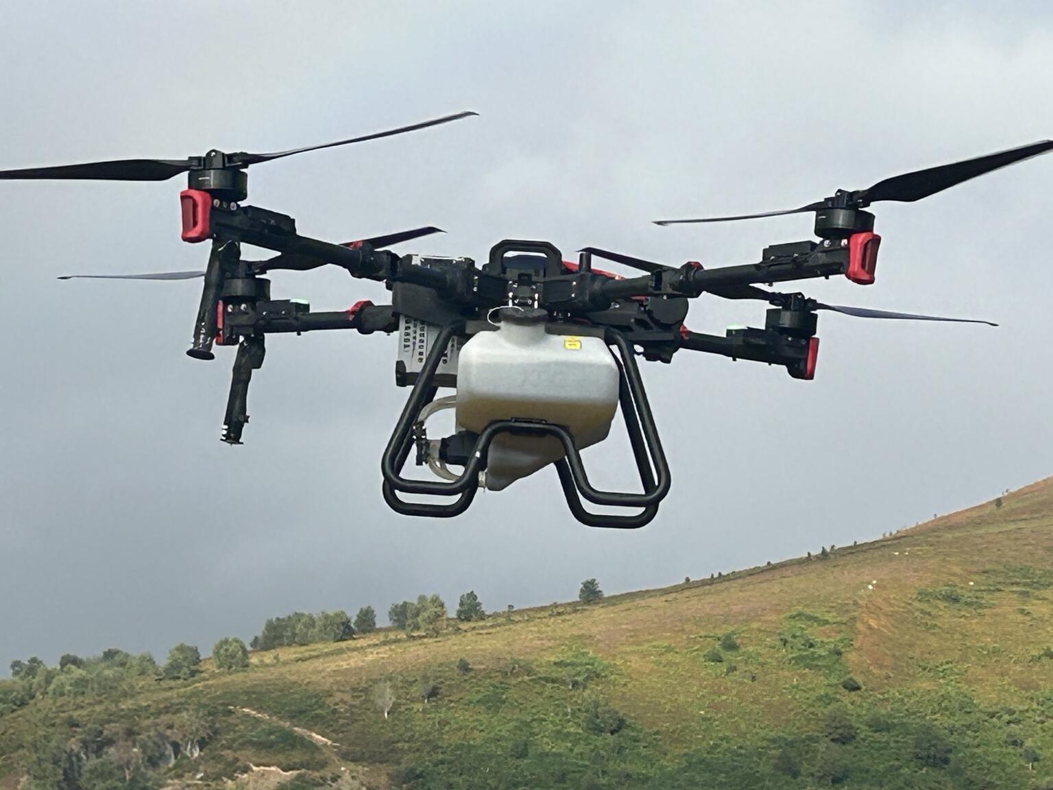 Heavy-lift agricultural application drone operating above a Welsh landscape